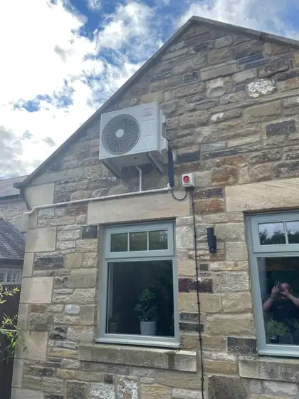 Condenser mounted on the gable of a stone cottage