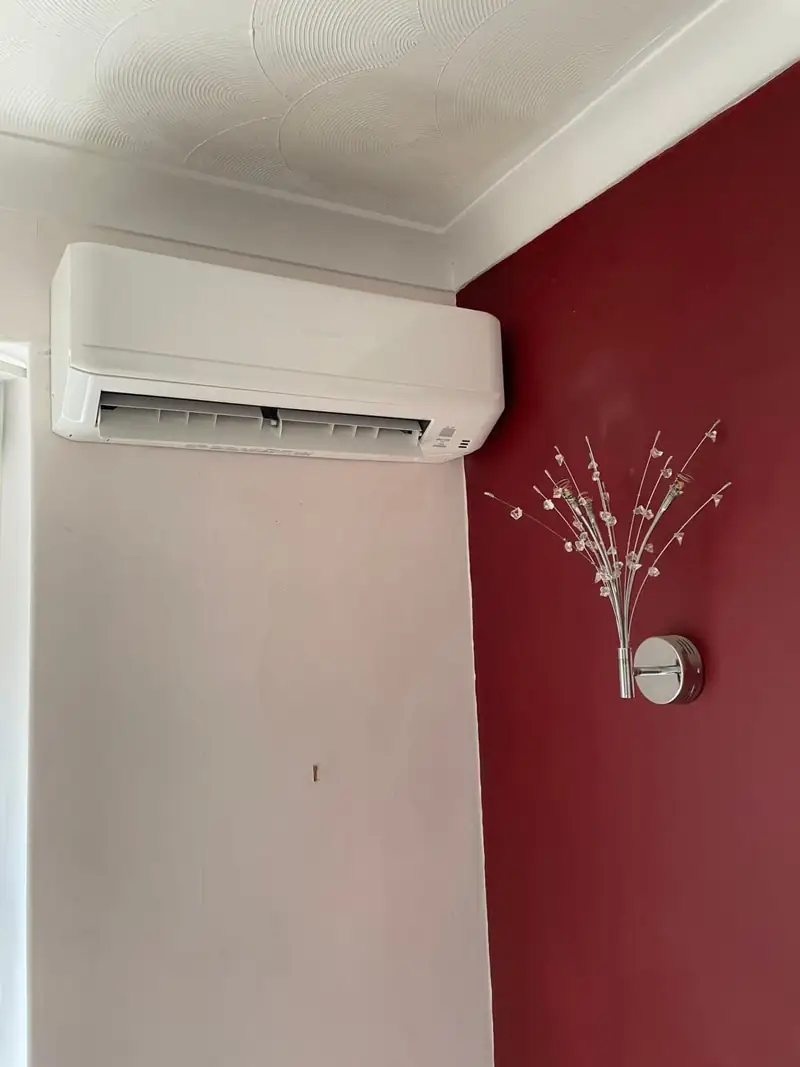 Clean, well-maintained split air conditioner on a red feature wall